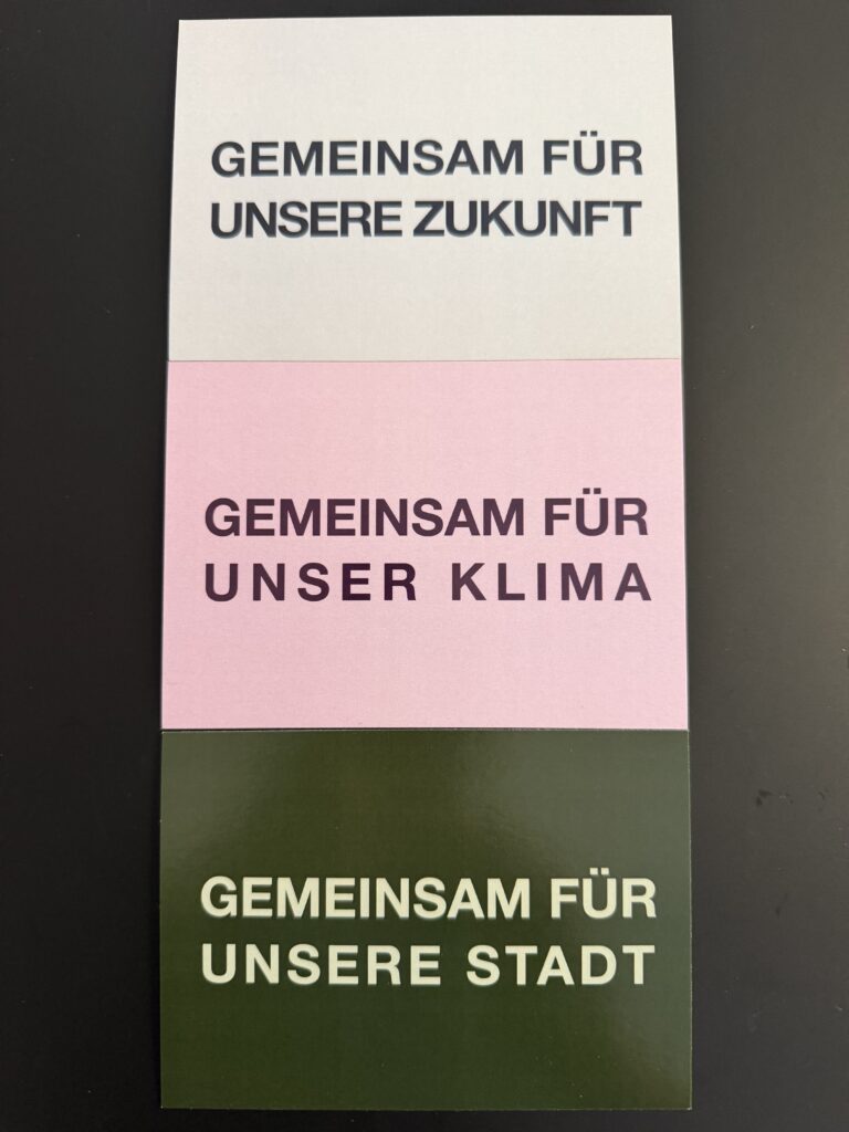 Das Foto zeigt unsere Flyer mit den Texten: „Gemeinsam für unsere Zukunft“, „Gemeinsam für unser Klima“, „Gemeinsam für unsere Stadt“.